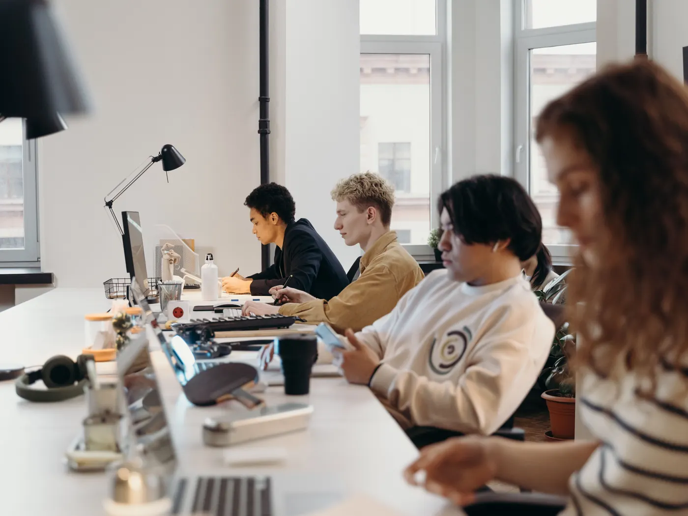 Ett team arbetar tillsammans vid ett långbord med bärbara datorer